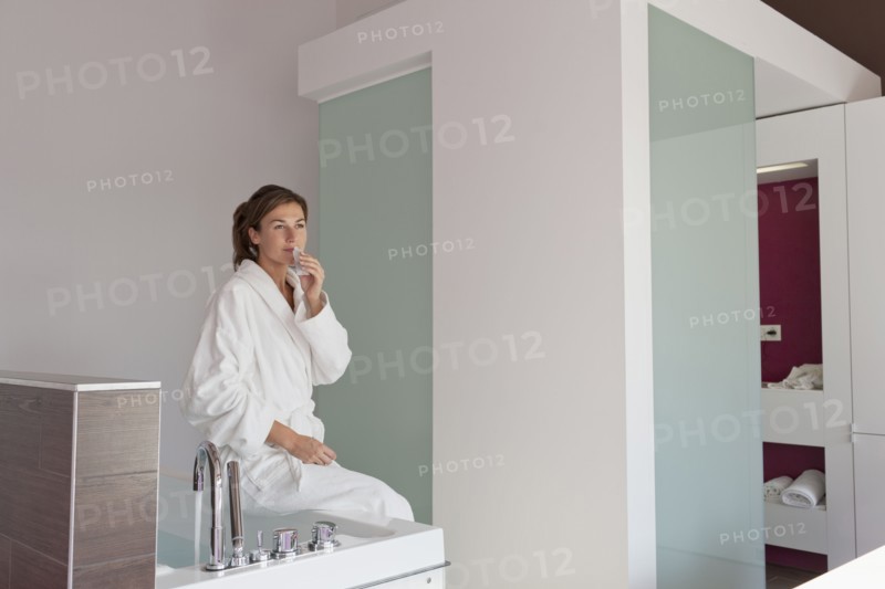 Woman in bathrobe sitting on tub. Photo : Jan Scherders