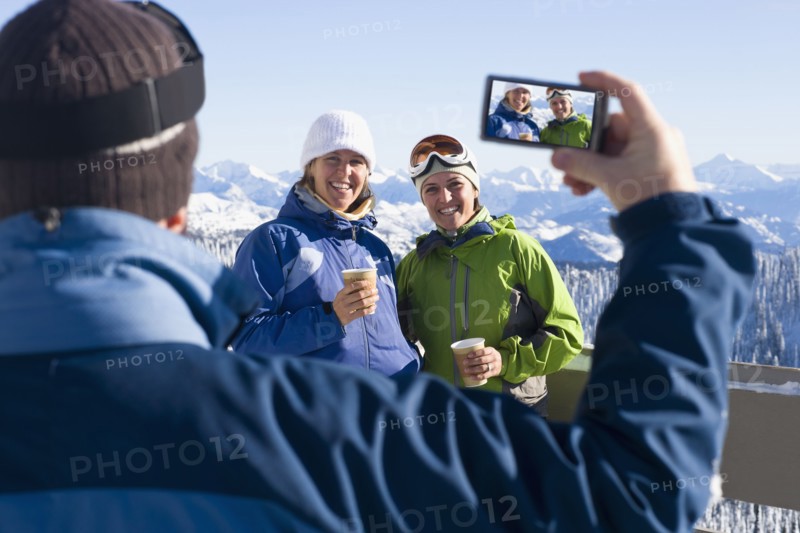 USA, Montana, Whitefish, Man photographing two women in mountain resort. Photo: Noah Clayton