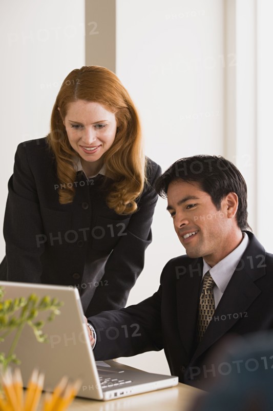 Businessman and businesswoman using laptop. Photo : Rob Lewine