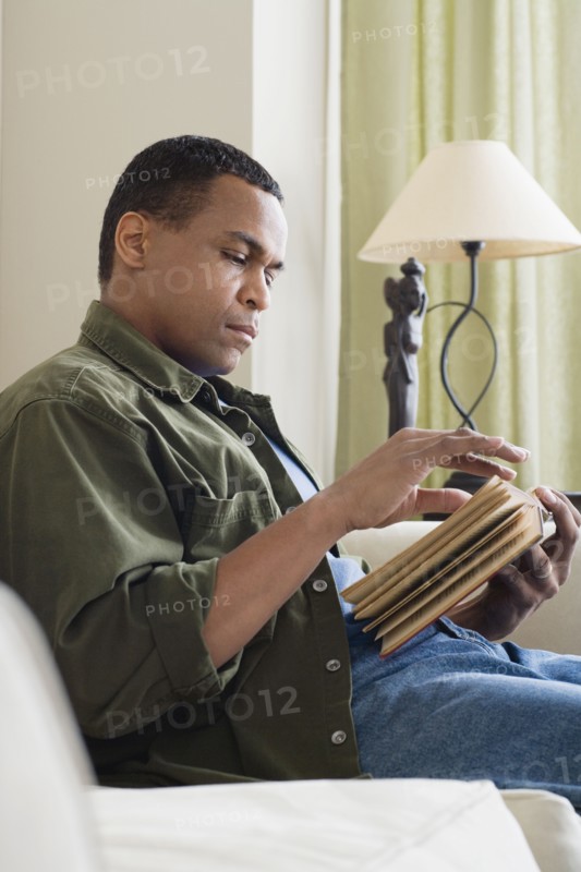 Man reading book at home. Photo : Rob Lewine