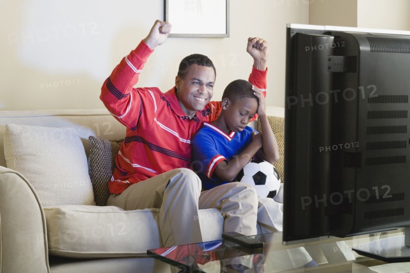 Father and Son (12-13) watching sports on tv. Photo : Rob Lewine