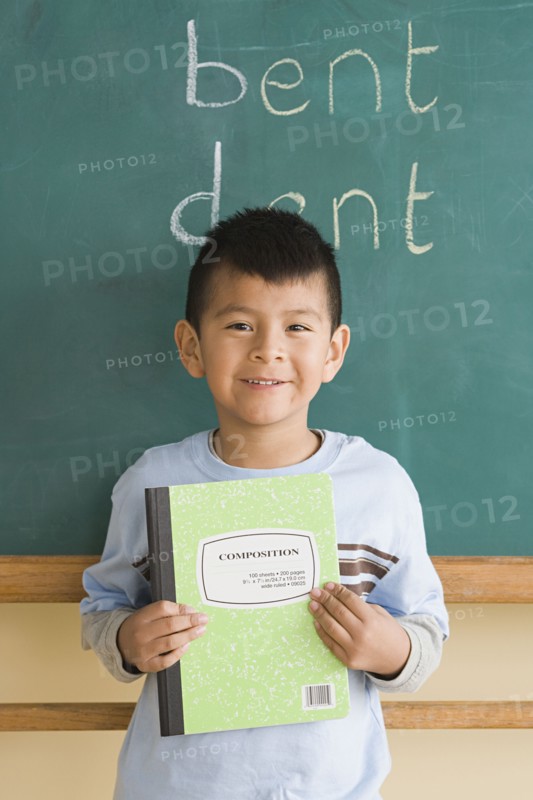 Smiling boy (6-7) showing notebook in classroom. Photo: Rob Lewine