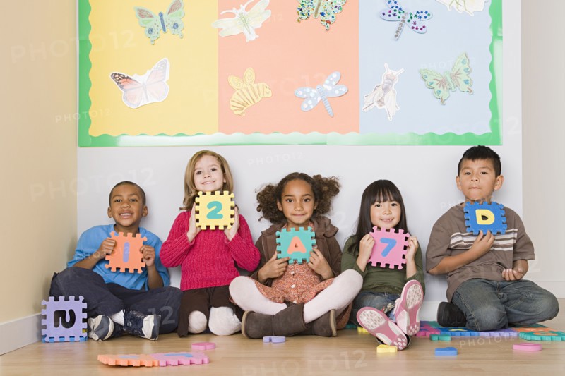 Children (6-7) sitting and holding letters in classroom. Photo : Rob Lewine