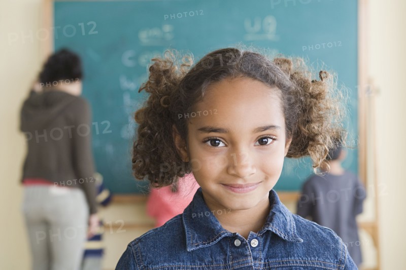 Portrait of smiling girl (6-7) with schoolmates in background. Photo : Rob Lewine
