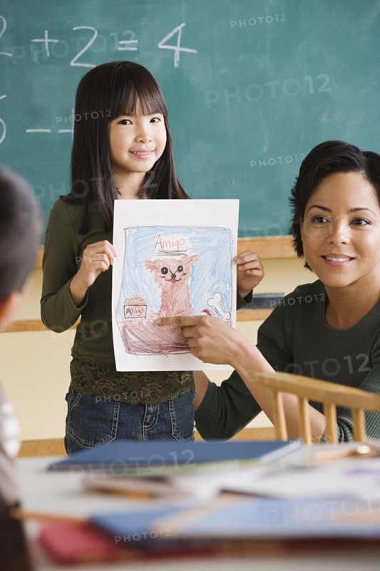 Girl (6-7) showing her drawing in classroom. Photo : Rob Lewine