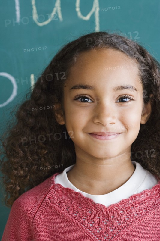 Portrait of schoolgirl (6-7) against blackboard. Photo : Rob Lewine