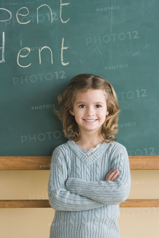Girl (6-7) in classroom against blackboard. Photo : Rob Lewine