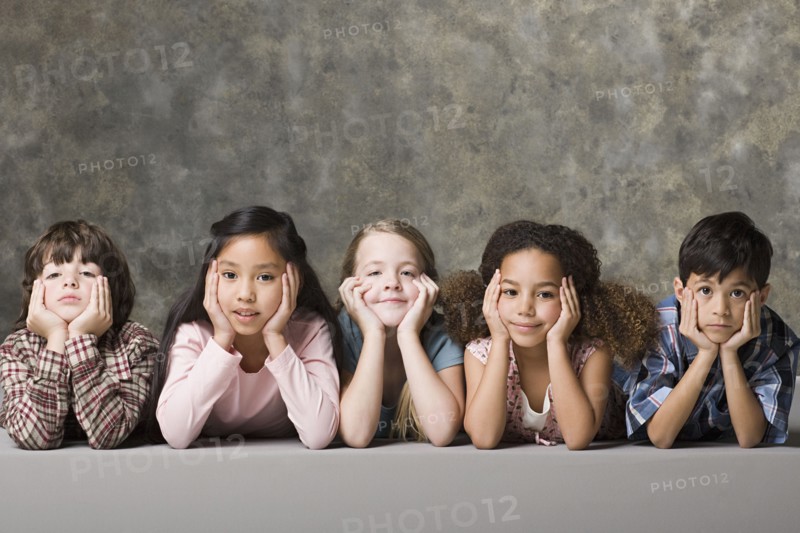 Children (6-7, 8-9) lying on floor, studio shot. Photo : Rob Lewine
