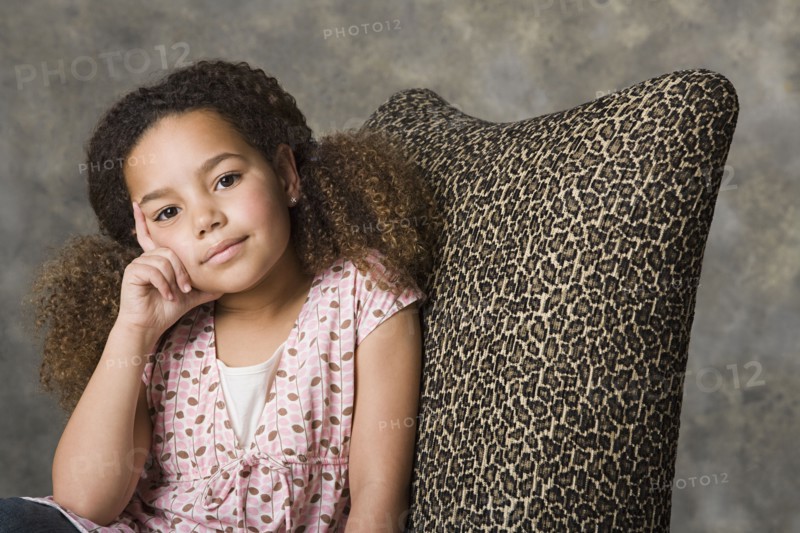 Portrait of thoughtful girl (8-9) sitting, studio shot. Photo: Rob Lewine