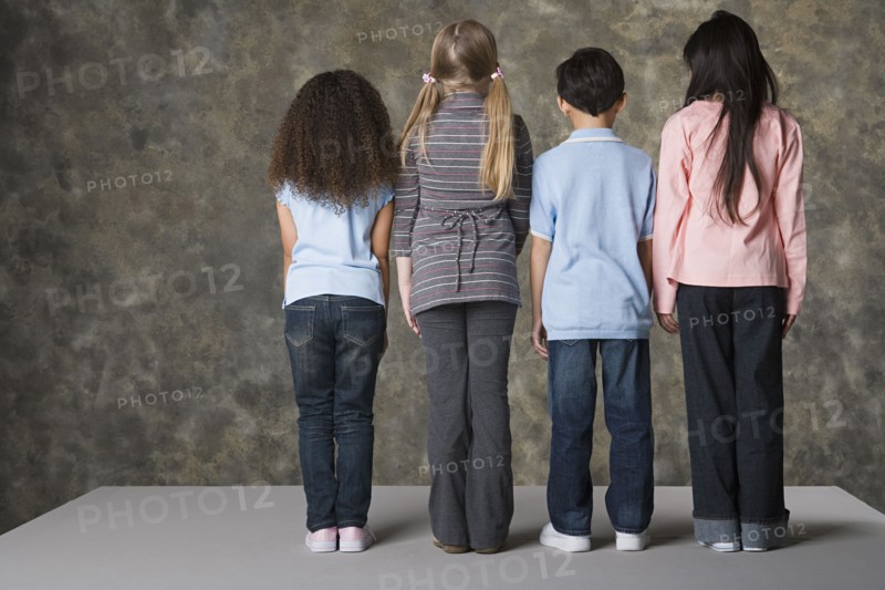 Rear view of children (8-9) standing, studio shot. Photo : Rob Lewine
