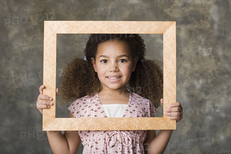 Portrait of smiling girl (8-9) holding picture frame, studio shot. Photo : Rob Lewine