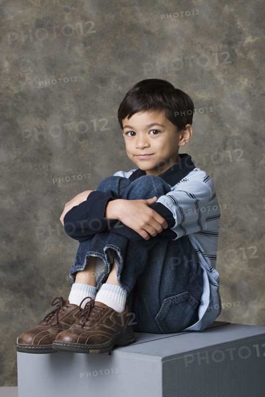 Smiling boy (8-9) standing, studio shot. Photo : Rob Lewine