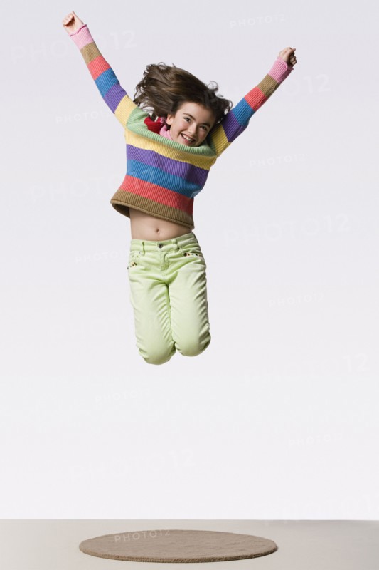 Happy girl (8-9) jumping, studio shot. Photo: Rob Lewine
