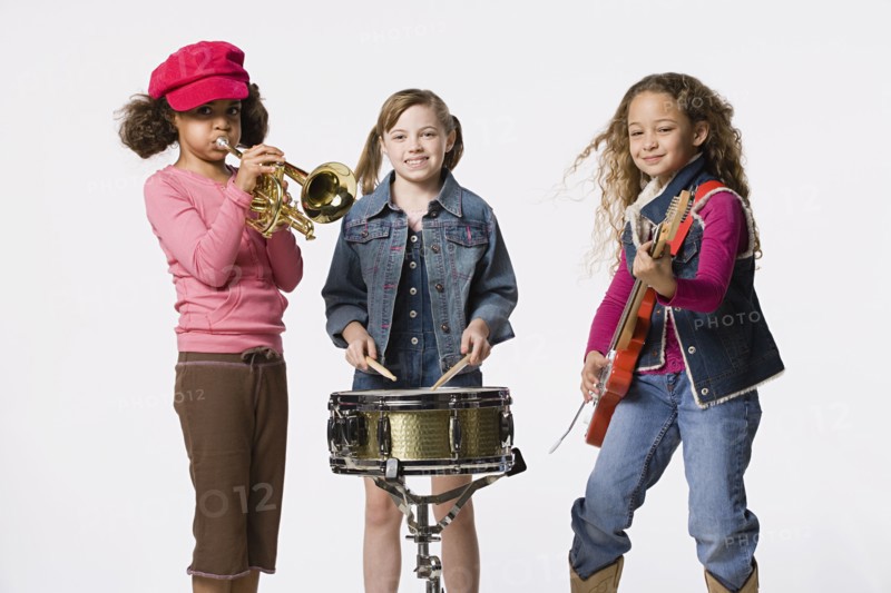 Three girls (8-9) playing instruments together, studio shot. Photo: Rob Lewine