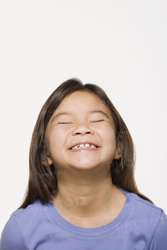 Portrait of smiling girl (8-9) with eyes closed, studio shot. Photo : Rob Lewine