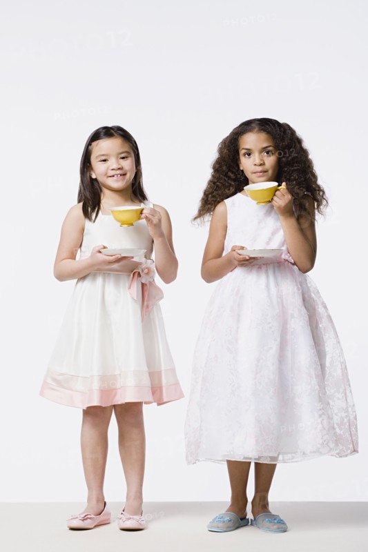 Two girls (8-9) wearing dresses and drinking tea, studio shot. Photo : Rob Lewine