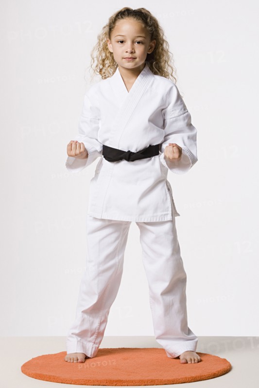 Studio portrait of smiling girl (8-9) wearing gi. Photo : Rob Lewine