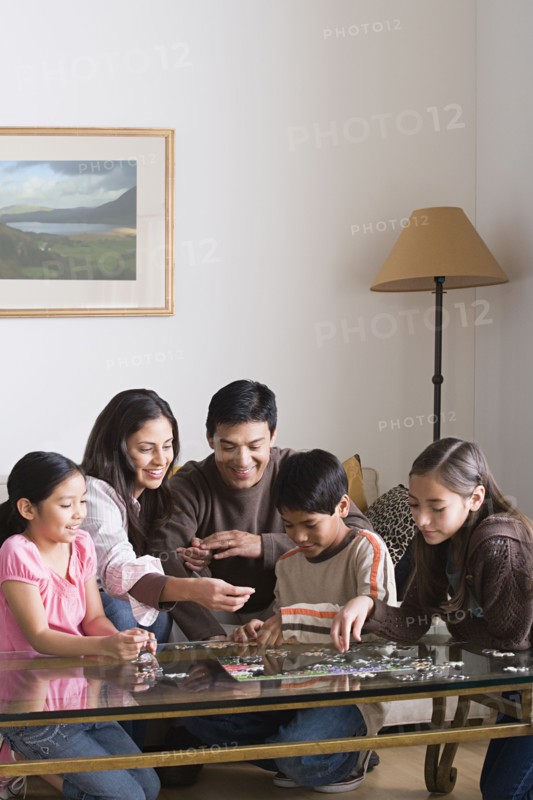 Family with three children (8-9, 10-11) playing with puzzle. Photo: Rob Lewine