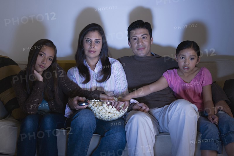 Family with two daughters (8-9, 10-11) watching tv on sofa. Photo: Rob Lewine