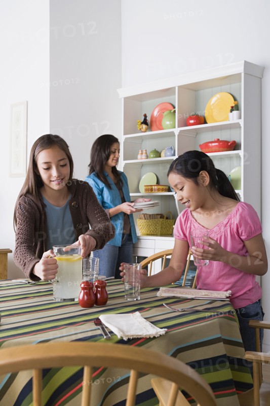 Mother with two daughters (8-9, 10-11) cleaning from table. Photo: Rob Lewine
