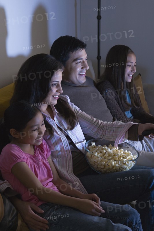 Family with two daughters (8-9, 10-11) watching tv on sofa. Photo: Rob Lewine