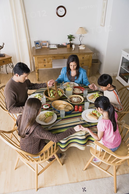 Family with three children (8-9, 10-11) praying at table. Photo : Rob Lewine