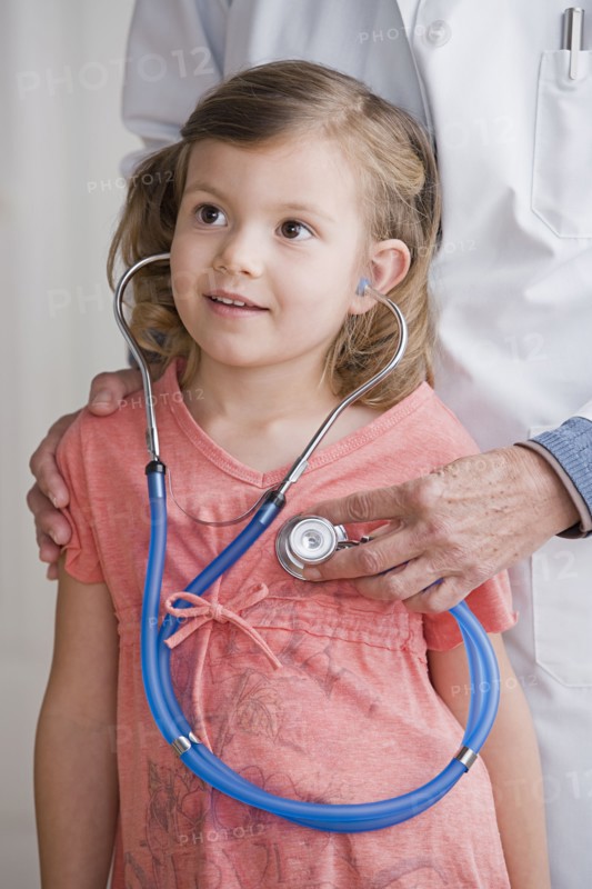 Female doctor with girl (4-5) listening to stethoscope. Photo : Rob Lewine