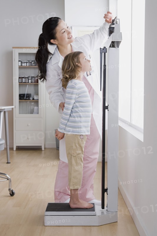 Female doctor measuring girl's (4-5) weight. Photo: Rob Lewine