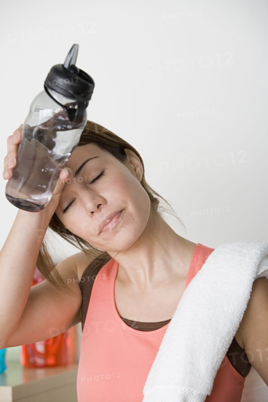 Tired female athlete wiping out sweat from forehead. Photo: Rob Lewine