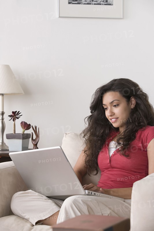 Young woman using laptop at home. Photo : Rob Lewine