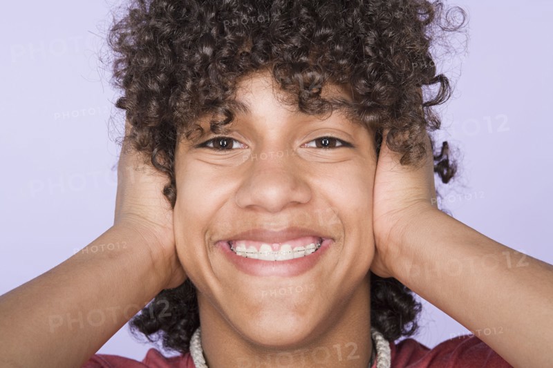 Portrait of teenage boy (14-15) covering ears with hands. Photo: Rob Lewine