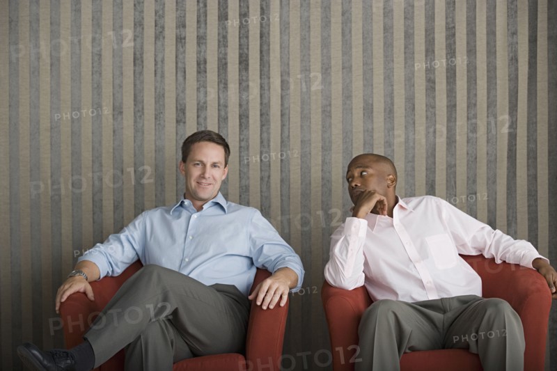 Two businessmen sitting on armchairs. Photo : Rob Lewine