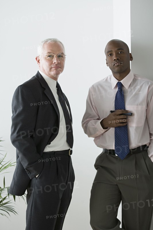 Two businessmen standing in office. Photo : Rob Lewine