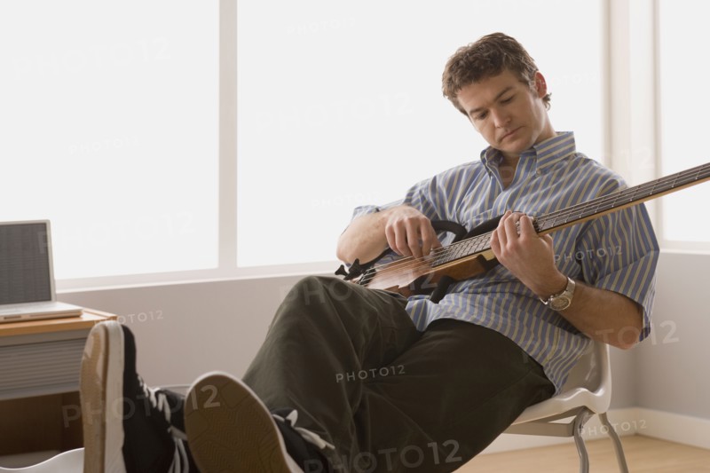 Young man playing electric base guitar. Photo : Rob Lewine