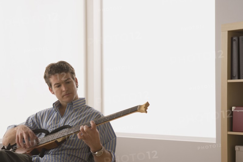 Young man playing electric base guitar. Photo : Rob Lewine