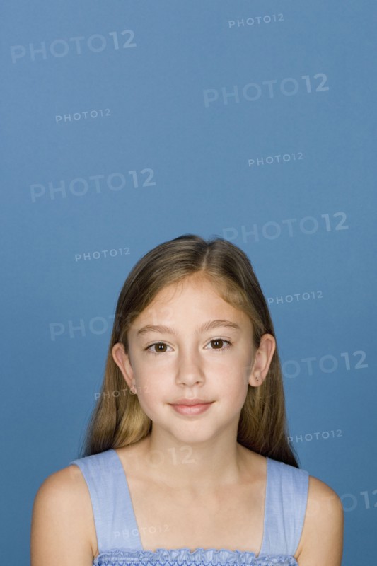 Portrait of happy girl (8-9) n blue background. Photo : Rob Lewine