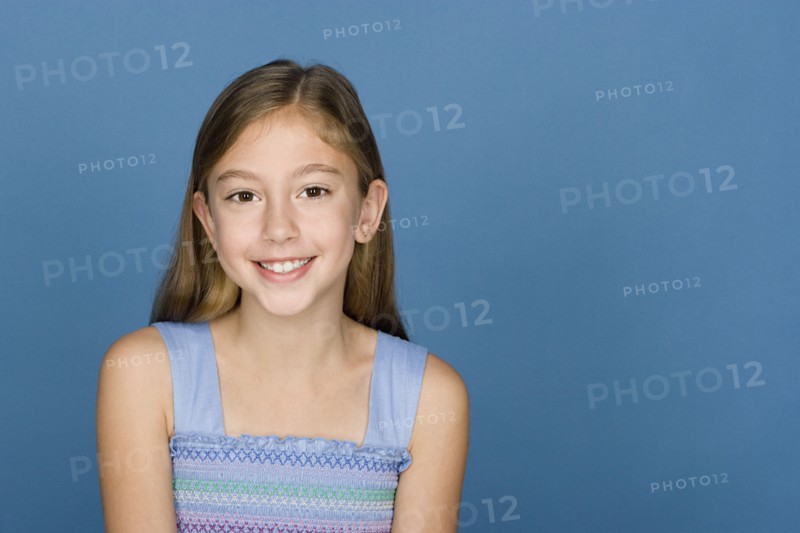 Portrait of happy girl (8-9) n blue background. Photo : Rob Lewine