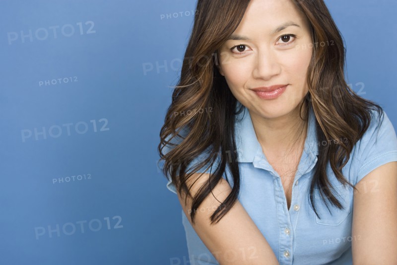 Portrait of smiling woman on blue background, studio shot. Photo : Rob Lewine