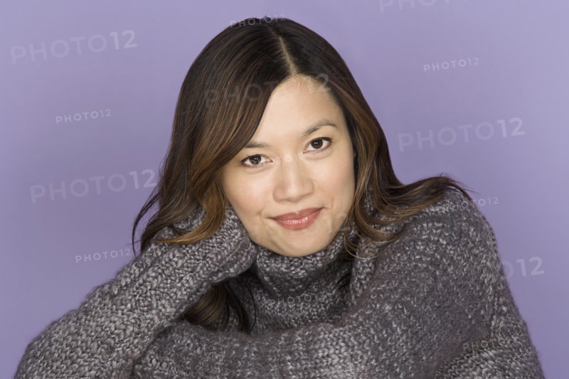 Portrait of smiling woman on purple background, studio shot. Photo : Rob Lewine