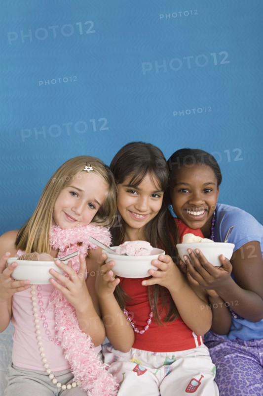 Portrait of three girls (10-11) holding desserts at slumber party. Photo : Rob Lewine