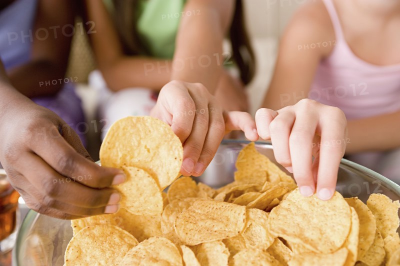 Three girls (10-11) reaching for crisps. Photo: Rob Lewine