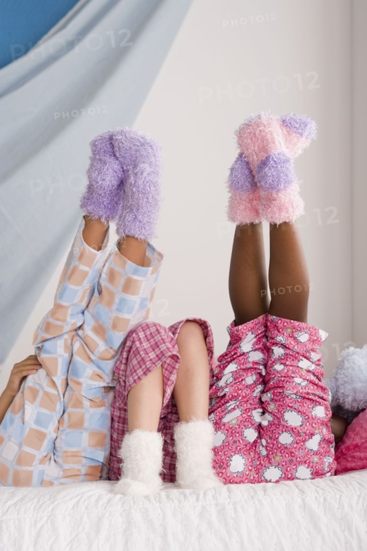 Close op of legs of three girls (10-11) lying on bed with feet up. Photo: Rob Lewine
