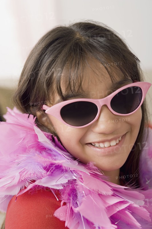Portrait of smiling girl (10-11) wearing feather boa and sunglasses. Photo: Rob Lewine