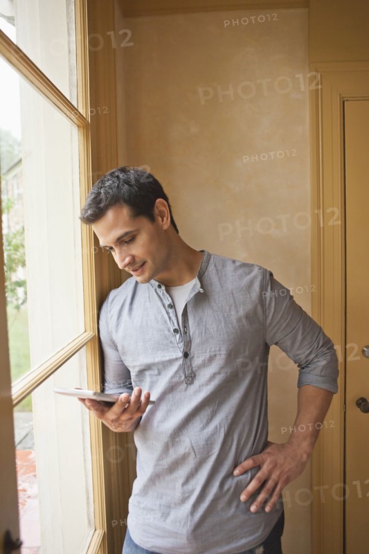 Man reading e-book at home. Photo : Tetra Images