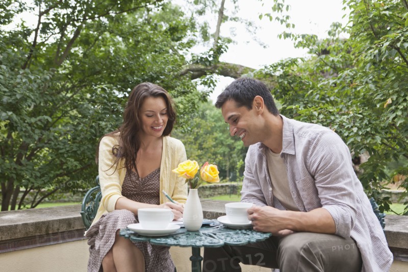 Happy couple sitting at table at outdoor cafe. Photo: Tetra Images