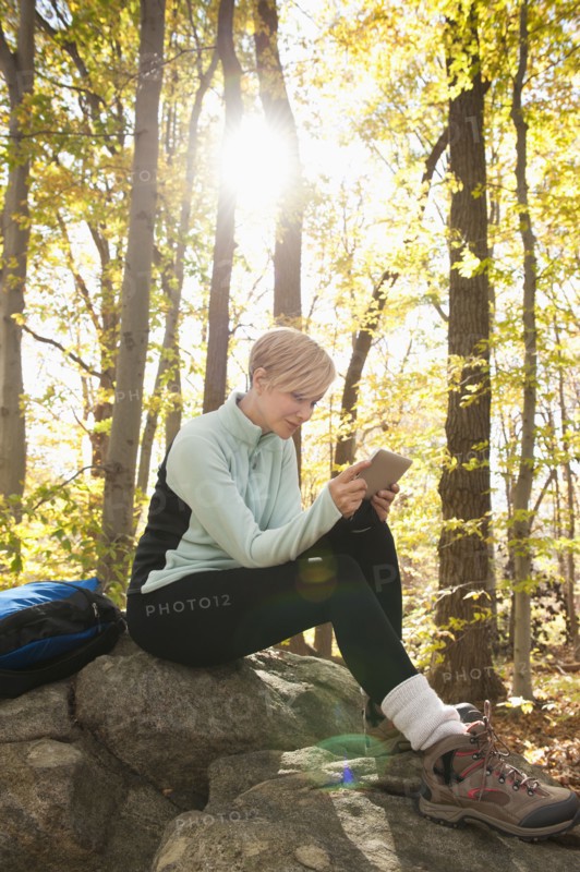 Female hiker using digital tablet in forest. Photo : Tetra Images
