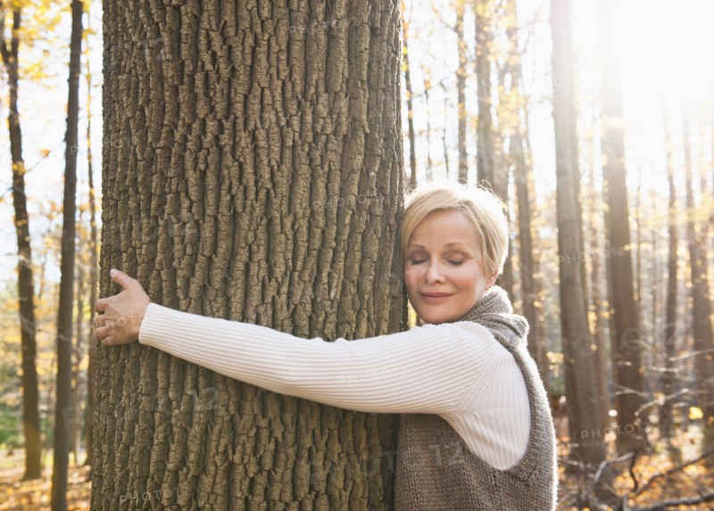 USA, New Jersey, Smiling woman hugging tree in Autumn forest. Photo : Tetra Images
