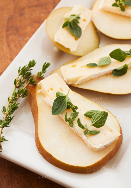 Studio shot of sliced pear with herbs.