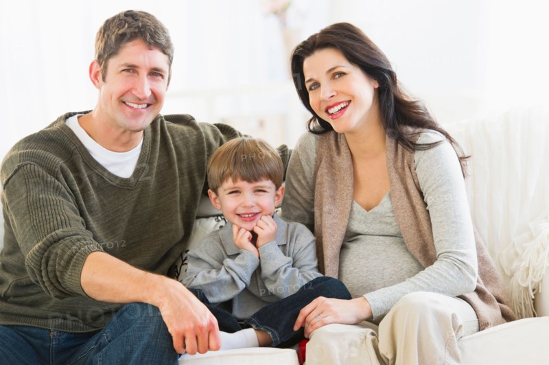 Portrait of parents with son (4-5) on sofa.