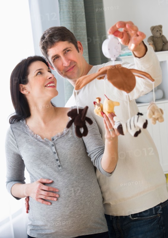 Expectant couple decorating baby room.
